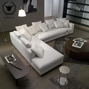 Удобный диван из белой сегментированной ткани в углу современной Г-образной комнаты